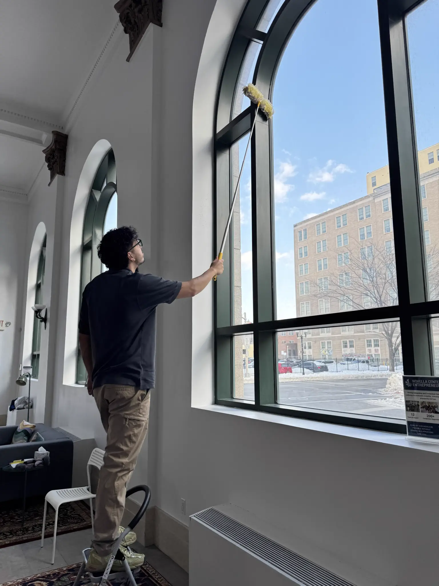 Alexander Morales cleaning high windows with extension tools